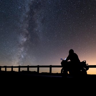 Fahrer auf einem E-Motorrad vor Sternenhimmel.