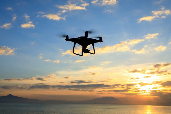 Eine Drohne fliegt vor dem Sonnenuntergang.