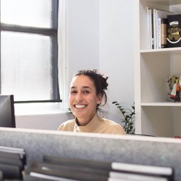 Eine Frau sitzt in einem Büro und lächelt.