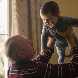 Ein älterer Mann hebt ein Kleinkind hoch.