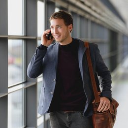 Ein Mann im Anzug telefoniert am Flughafen.